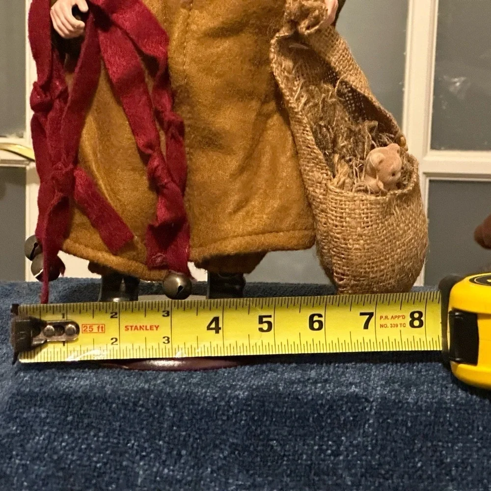 Shaggy haired and bearded Santa wears a brown cape and carries a burlap sack.